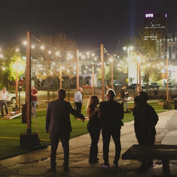 A Group Of People Standing On A Sidewalk