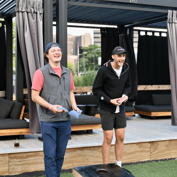 A Couple Of People That Are Standing In Front Of A Cabana And Playing Cornhole